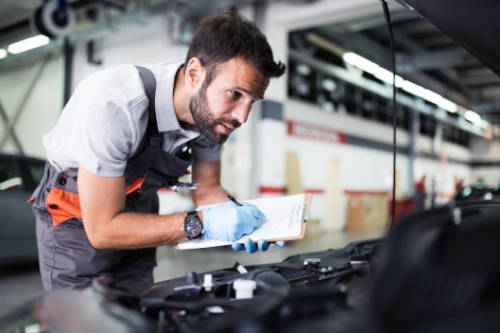 Mechaniker schaut in den Motorraum eines PKW